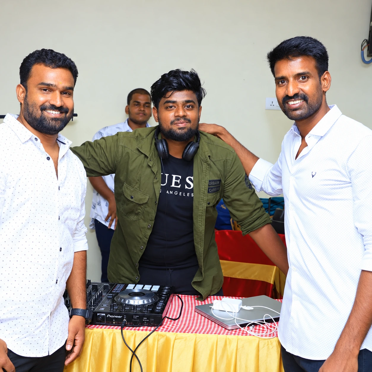 Three men together behind a Pioneer DJ controller at an indoor event