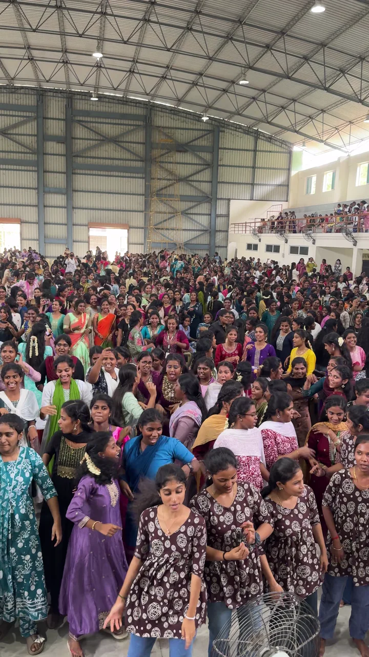 A packed college hall seen from the DJ stage as the crowd joins the music