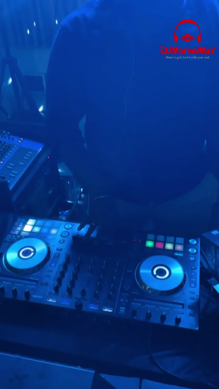 DJ equipment and guests enjoying colourful dance-floor lighting