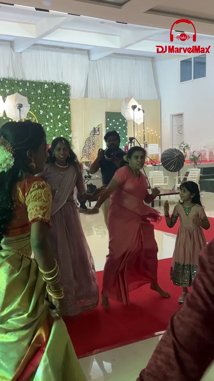 Guests dancing together beside the illuminated DJ booth at a reception