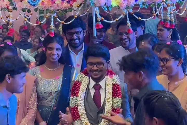 A wedding couple celebrating with guests beneath a flower-decorated umbrella