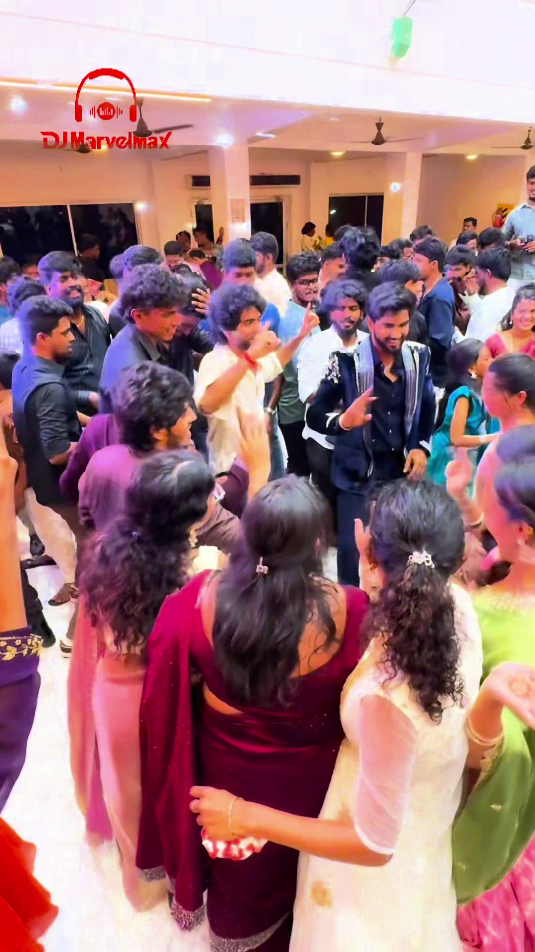 Wedding guests filling the dance floor around the DJ beneath warm venue lights