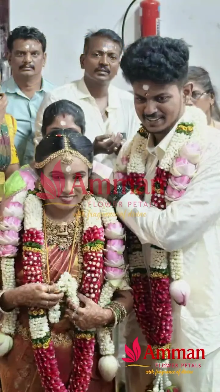 A bride and groom wearing traditional flower garlands with family at their wedding