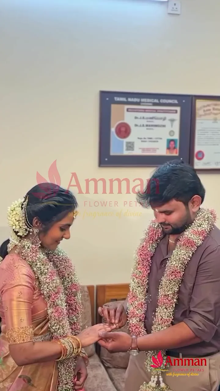 A wedding couple wearing pink and white flower garlands during their ceremony