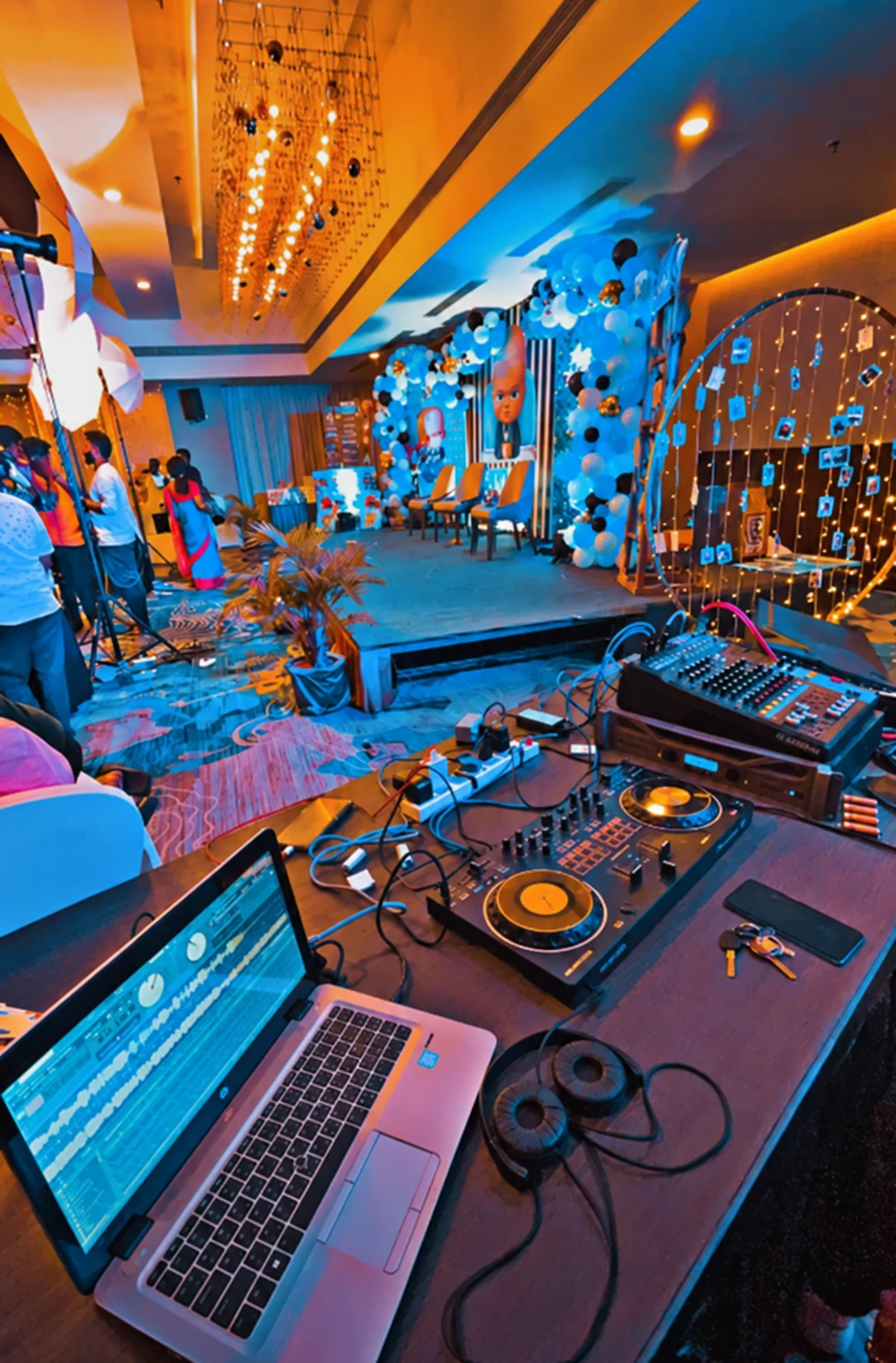 DJ console and laptop beside a decorated indoor event stage